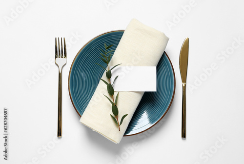 Stylish table setting with cutlery, blank card and eucalyptus leaves on white background, flat lay photo