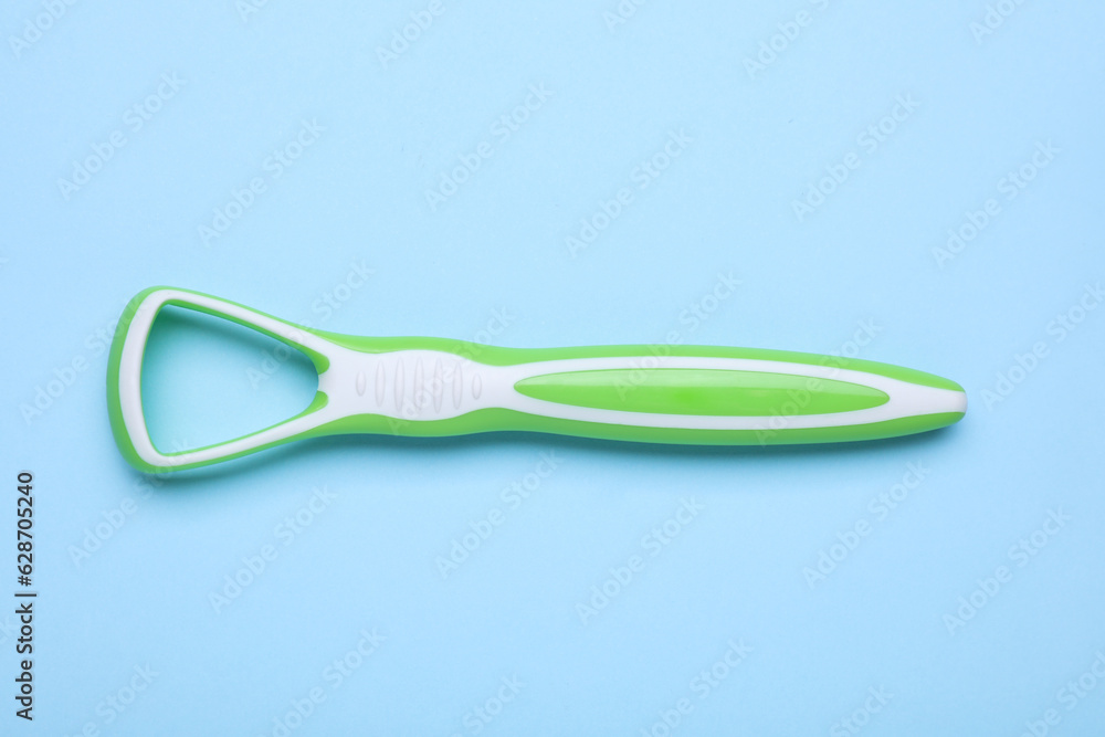 Green tongue cleaner on light blue background, top view Green tongue cleaner on light blue background, top view