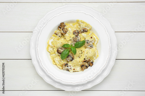 Delicious ravioli with mushrooms and cheese on white wooden table, top view