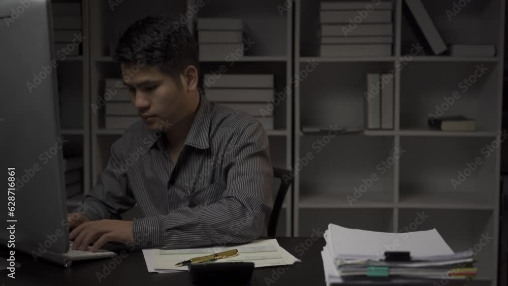 Asian male businessman working with financial documents and desktop computer till late at office, young man working overtime salaryman concept 4k Asian male businessman working with financial documents and desktop computer till late at office, young man working overtime salaryman concept 4k