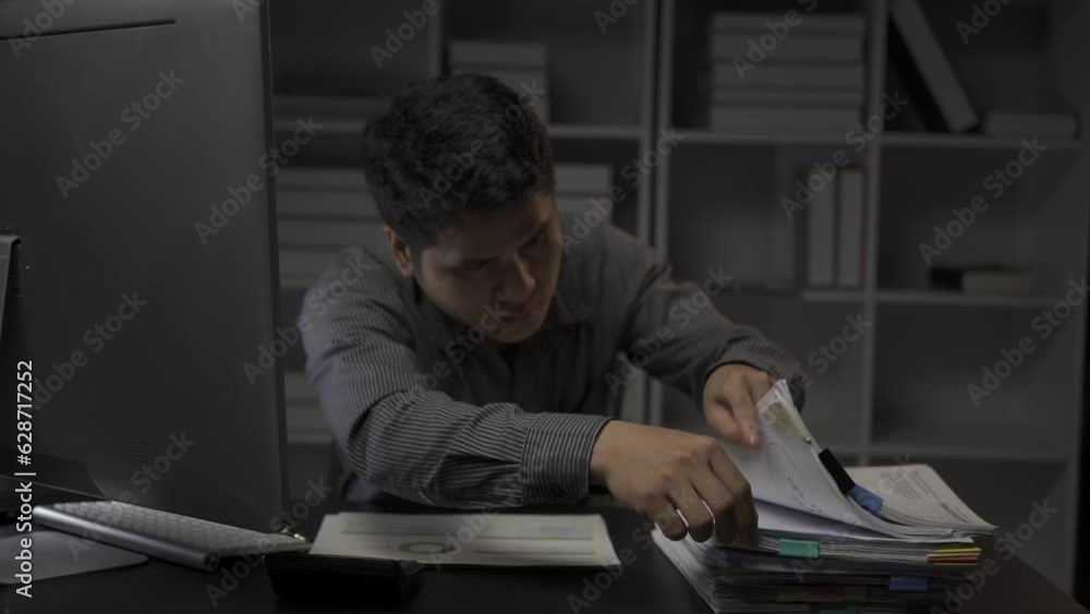 Asian male businessman working with financial documents and desktop computer till late at office, young man working overtime salaryman concept 4k Asian male businessman working with financial documents and desktop computer till late at office, young man working overtime salaryman concept 4k