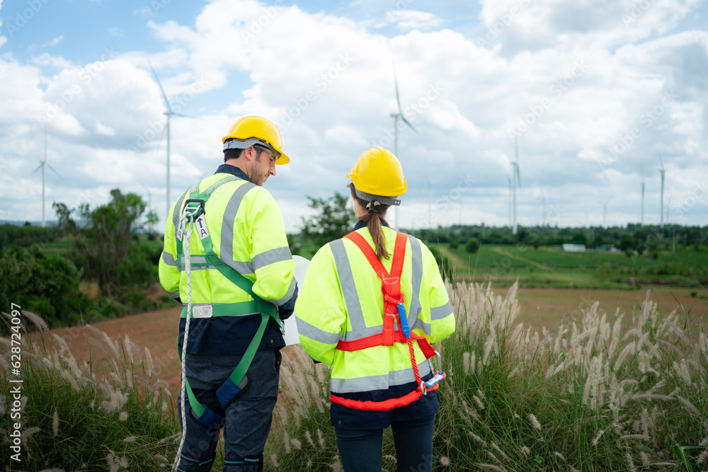 Engineer and worker discussing the project on the background of wind turbines Engineer and worker discussing the project on the background of wind turbines