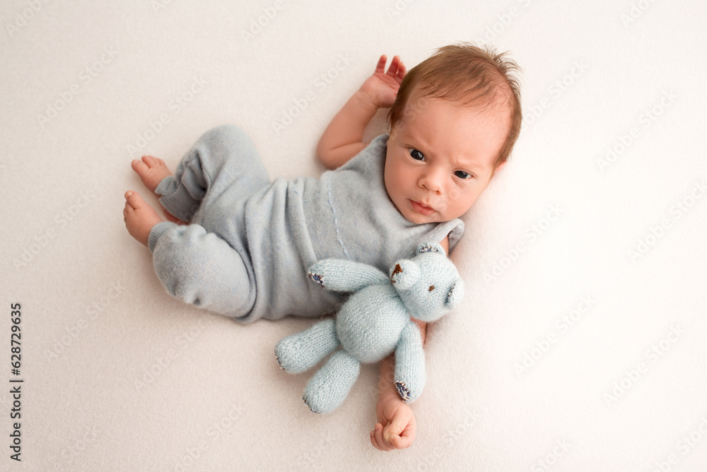 A cute newborn baby boy lies in a blue overalls in the first days of life. A cute newborn baby boy lies in a blue overalls in the first days of life.