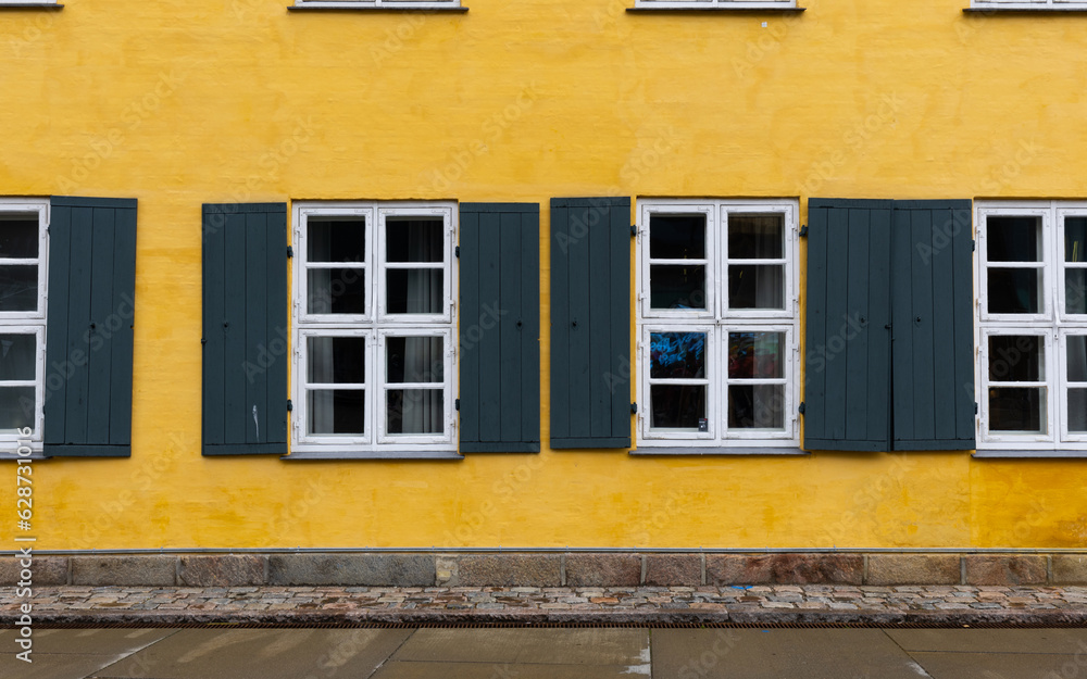 White and green window on yellow wall.
