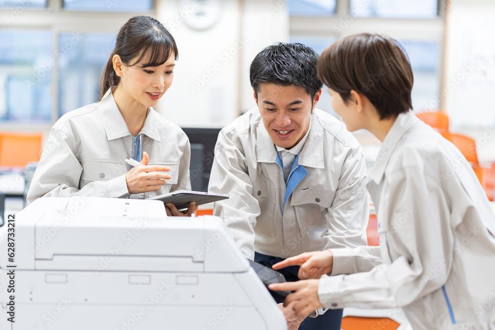 コピー機を点検する作業着を着た日本人 コピー機を点検する作業着を着た日本人