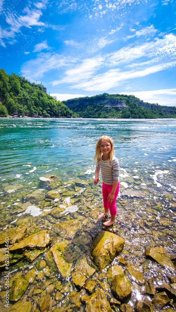 Girl standing in the blue water of a Niagra lake during hot summer day