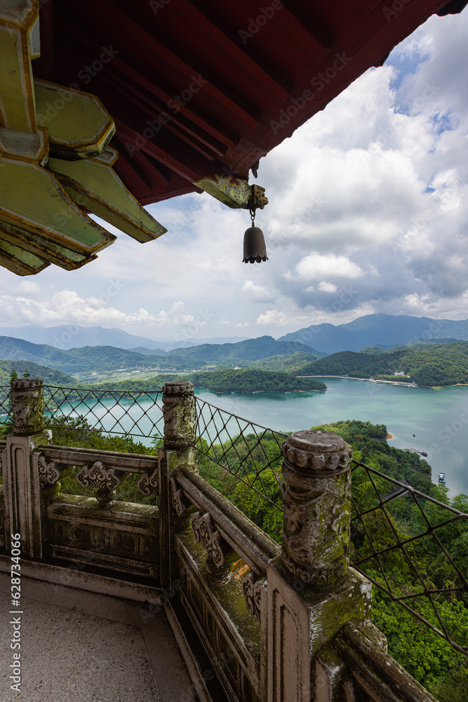 From Ci'en Pagoda, mesmerizing vista unfolds, panoramic view of Sun Moon Lake Taiwan, with surrounding mountain landscape. The tranquil lake mirrors the sky, while lush green peaks embrace its shores