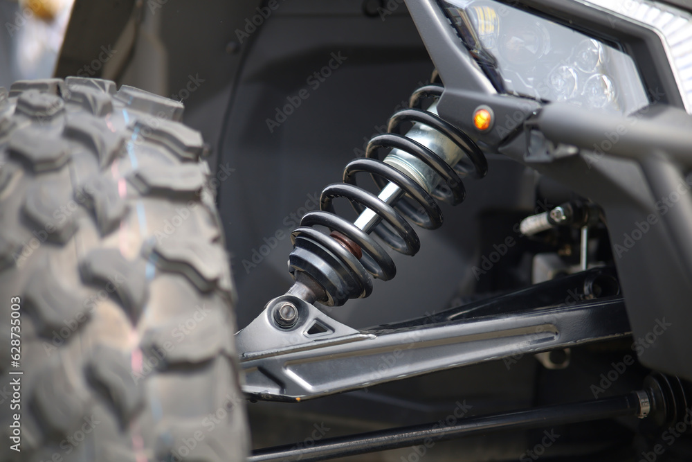 Close-up of new suspension system and shock absorber of car with wheel. Automotive part of atv off road. Mechanical engineering industry concept. 