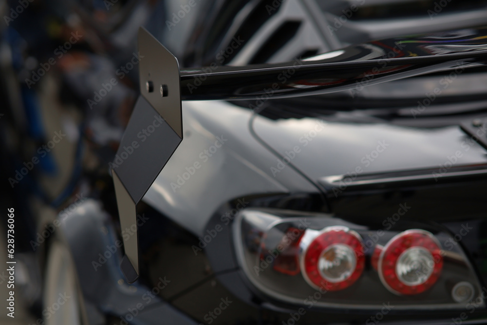Sport car at the start. Grille on the rear window of the car. Luxury black sports car fragment, rear aerodynamics carbon spoiler and rear lights.