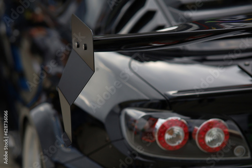 Sport car at the start. Grille on the rear window of the car. Luxury black sports car fragment, rear aerodynamics carbon spoiler and rear lights. © Евгений Бордовский