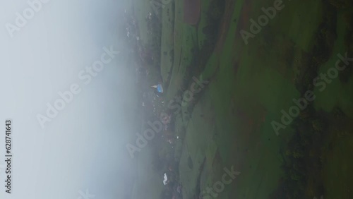 Vertical moody aerial shot of old church in enveloping mist on a green field photo