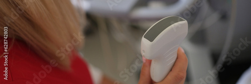 Female doctor holds ultrasound scanner device for examining patient in her hand.