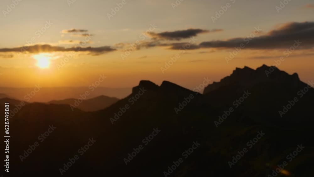 Sunset over the mountains. Timelapse of sunset with clouds on the background of mountain peaks silhouette. Blurred video Sunset over the mountains. Timelapse of sunset with clouds on the background of mountain peaks silhouette. Blurred video