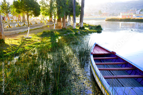 rustic boat on lake with trees and sun rays in summer in la paz bolivia hispanic america photo