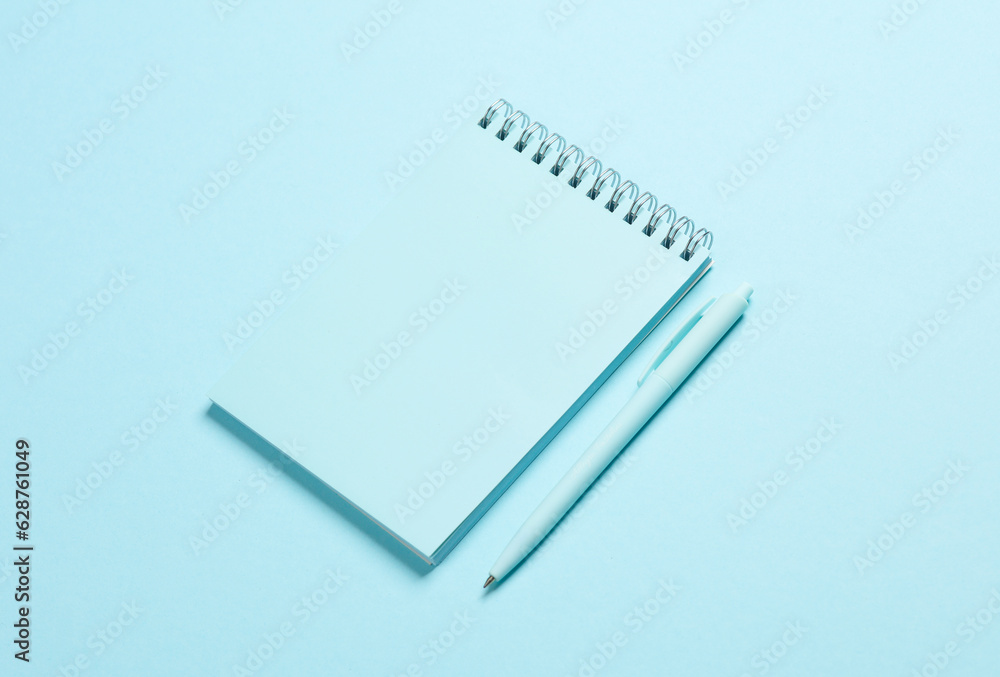 Blue notebook with a pen on a blue background Blue notebook with a pen on a blue background