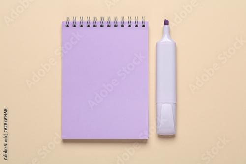 Notebook with a marker on a beige background. Top view