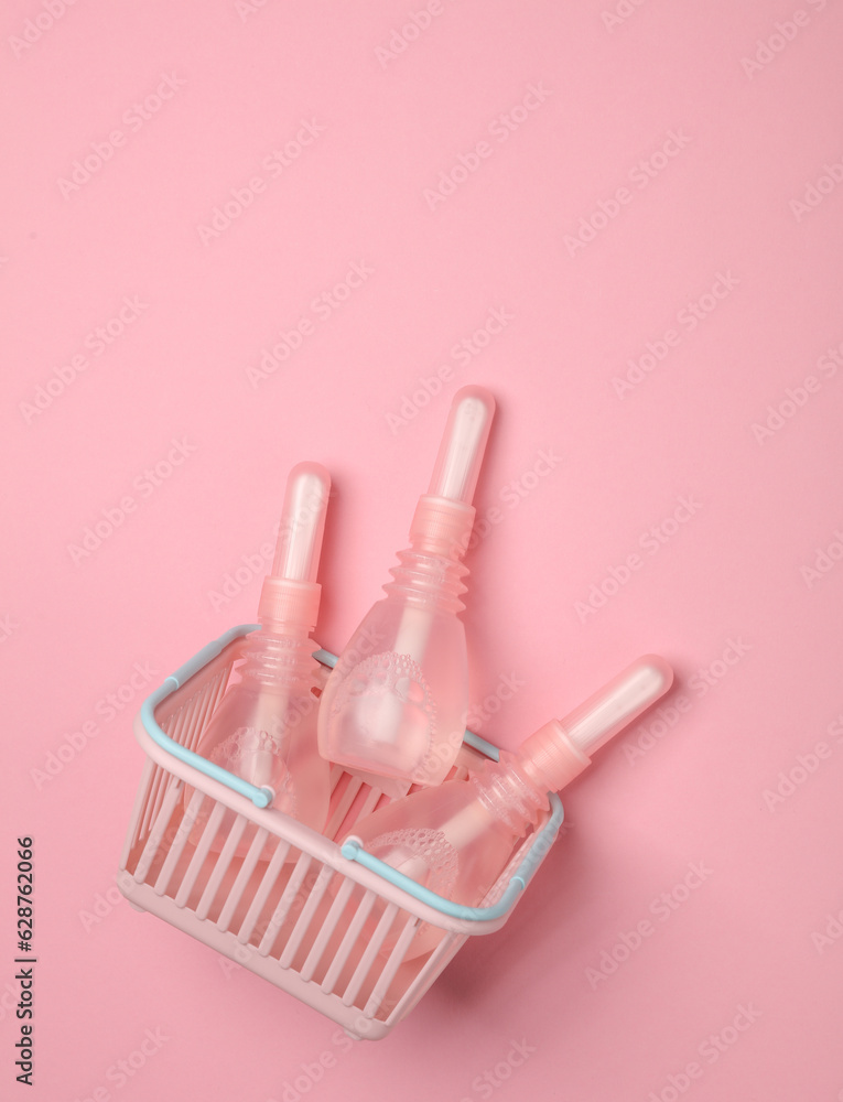 Supermarket basket with three vaginal enemas on a pink background. Women's health Supermarket basket with three vaginal enemas on a pink background. Women's health