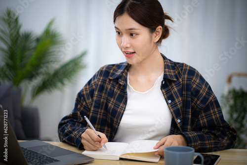 Happy beautiful Asian woman using computer laptop for work online at living room