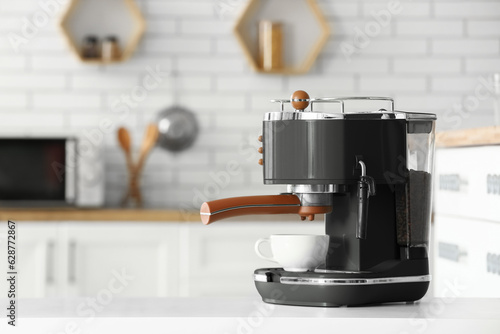 Foto Modern coffee machine with cup on white table in kitchen