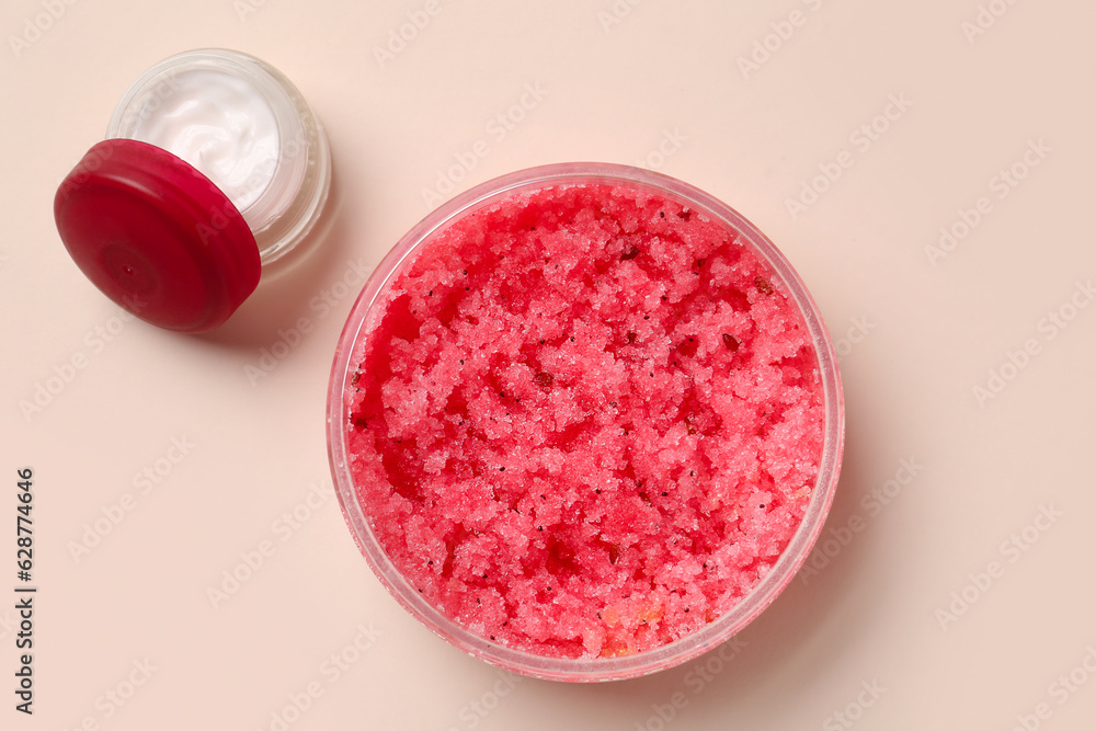 Jars with body scrub and cream on color background Jars with body scrub and cream on color background