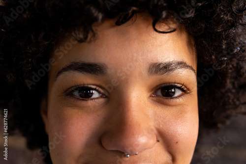 Portrait of happy biracial casual businesswoman with nose piercing smiling at office photo