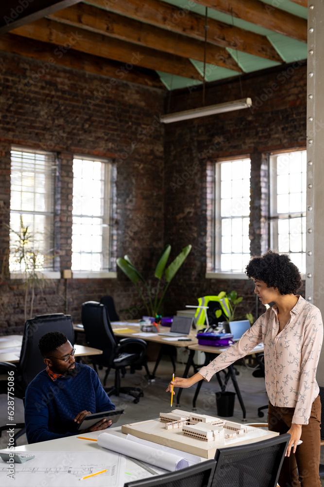 Diverse male and female architects discussing building model and using tablet at office, copy space Diverse male and female architects discussing building model and using tablet at office, copy space