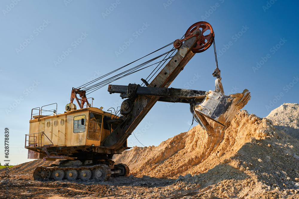 Shovel mining excavator takes chalk from pile in open quarry