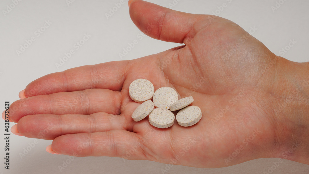 Different types of pills in a woman's hand