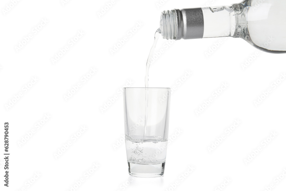 Pouring of vodka from bottle into glass on white background Pouring of vodka from bottle into glass on white background