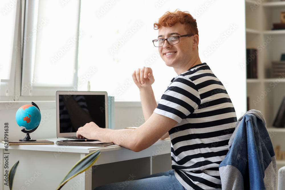 Fototapeta premium Young redhead man studying with laptop at home