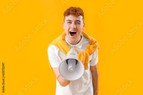 Photos Young redhead man shouting into megaphone on yellow background