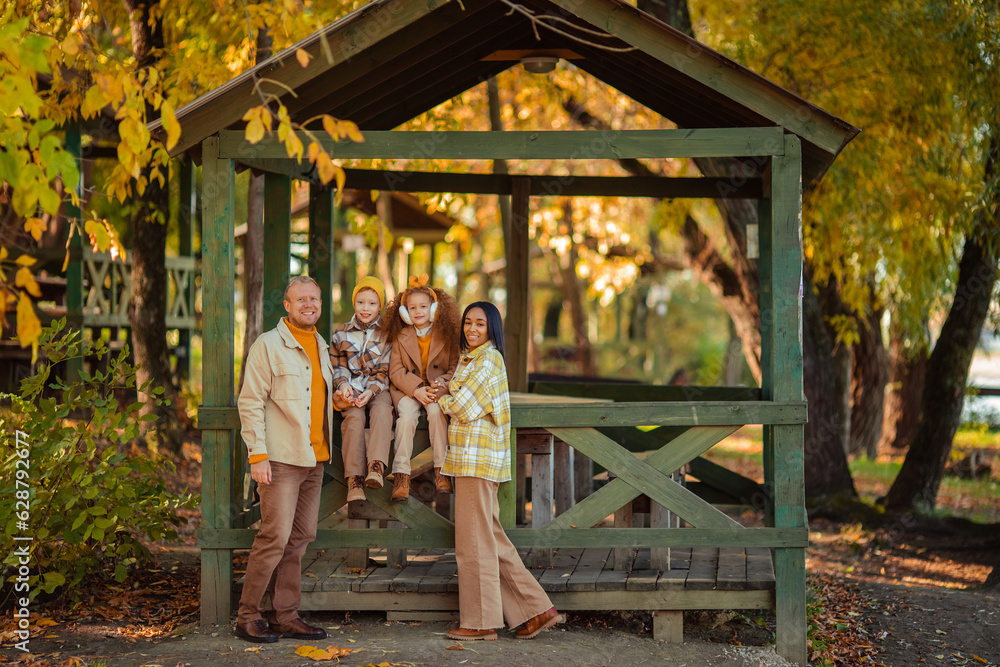 multiethnic family on a walk in the autumn park in a wooden gazebo multiethnic family on a walk in the autumn park in a wooden gazebo