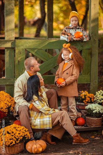 family traditions. multiethnic family i am in autumn in the park in a wooden gazebo next to pumpkins and flowers