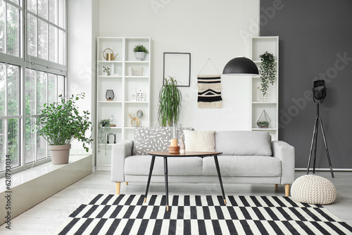 Interior of stylish living room with grey sofa, coffee table and big window
