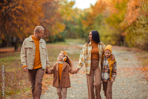 happy multiethnic family in autumn on a walk in the park in warm clothes