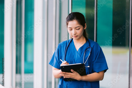 Asian nurse or doctor with stethoscope and clipboard in hospital.