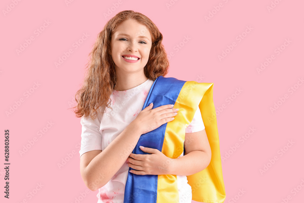 Beautiful happy young woman with Ukrainian flag on pink background Beautiful happy young woman with Ukrainian flag on pink background