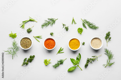 Foto Composition with bowls of spices and fresh herbs on light background