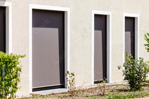 Window Blinds. Modern Fabric Roller Blind on Large Panoramic Windows Door. External Shutters on Window or Terrace Door.