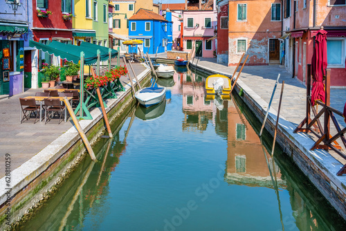 Picturesque colorful idyllic scene with a boats docked on the water canals in Burano Venice Italy. Water reflection. © Cristi