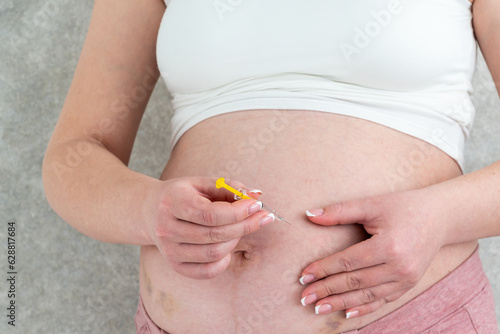 Pregnant woman making injection in stomach