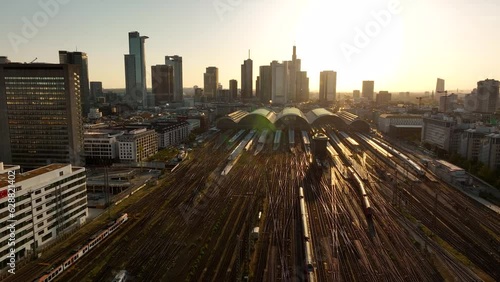 AERIAL: Frontal flight over Frankfurt am Main early morning in yellow-brown range. Central train station Germany, train tracks with low traffic. High angle view of the station building. photo