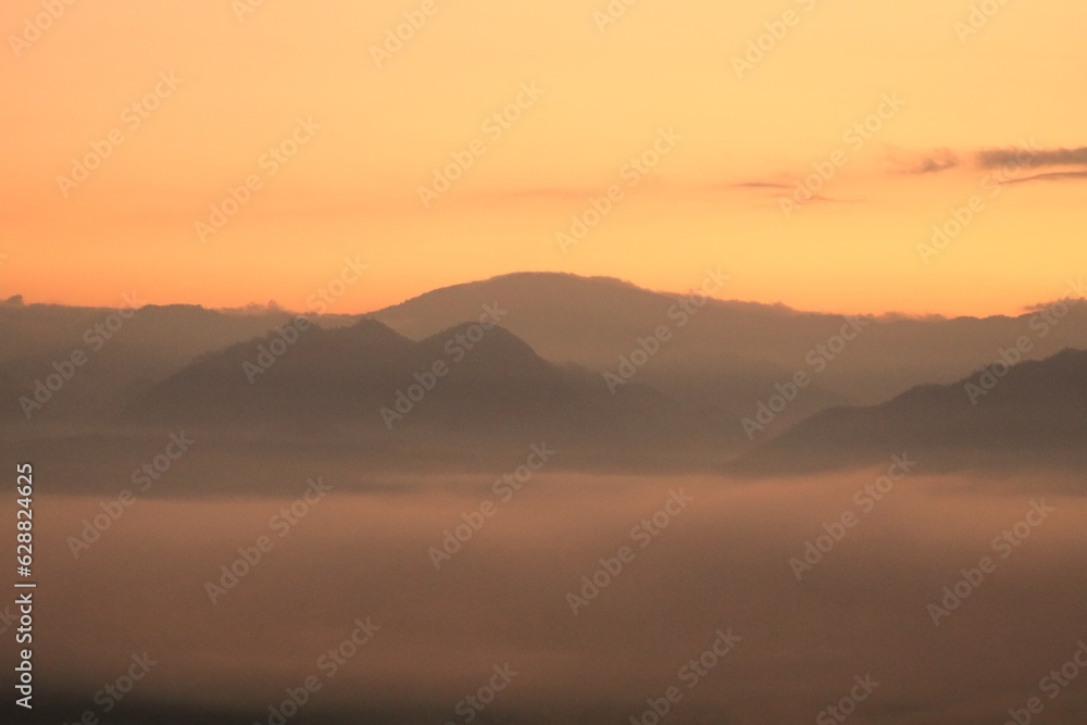 Before sunrise, white fog, mountains, and beautiful orange sky scenery