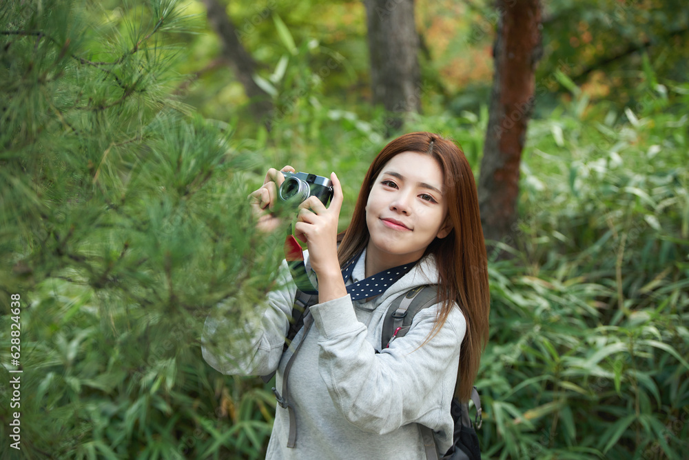 A young woman walking around in the woods taking pictures with a camera and backpack A young woman walking around in the woods taking pictures with a camera and backpack