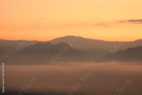 Before sunrise, white fog, mountains, and beautiful orange sky scenery