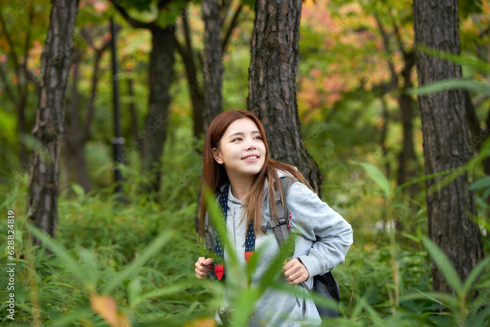 A young woman walking around in the woods taking pictures with a camera and backpack A young woman walking around in the woods taking pictures with a camera and backpack