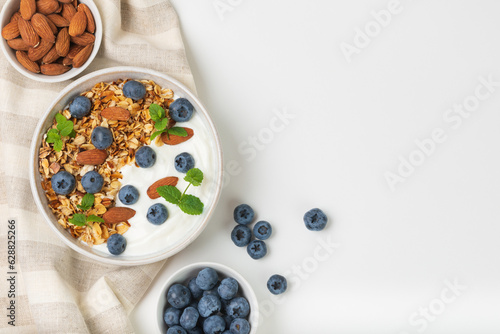 Granola with yogurt, blueberries and almond in bowls on a white background top view with copy space photo