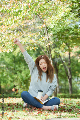 a young woman sitting in a forest park  drinking coffee and reading