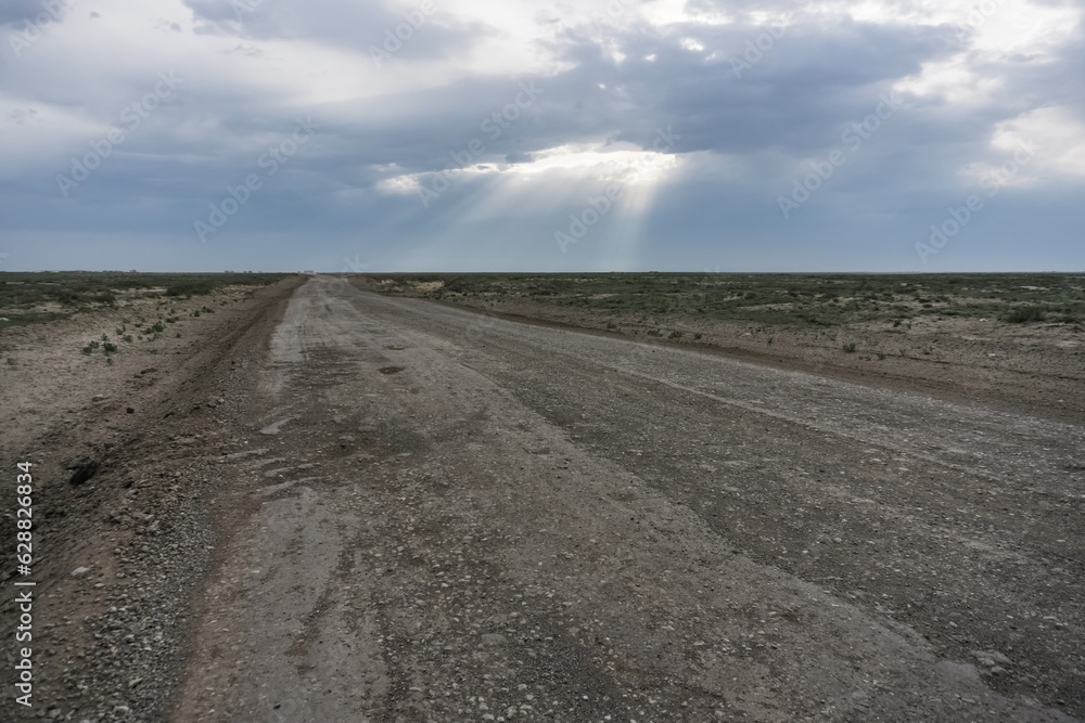 Through a dense layer of clouds and clouds, the sun's rays break through in the desert steppe, in cloudy weather.