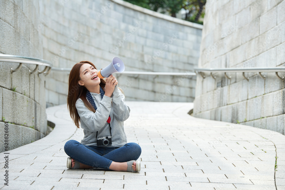 a young woman who sits on the road and guides her through a loudspeaker with a camera around her neck